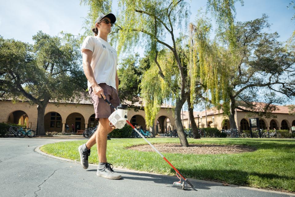 Un promeneur malvoyant se dirigeant dans un parc grâce à la Canne Augmentée